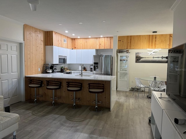 kitchen featuring kitchen peninsula, a kitchen breakfast bar, stainless steel appliances, and light hardwood / wood-style flooring