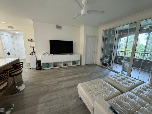 living room with wood-type flooring, ornamental molding, and ceiling fan