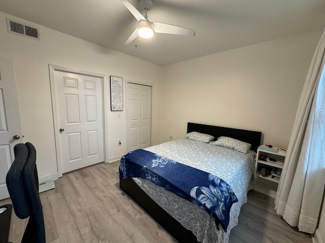 bedroom with hardwood / wood-style flooring, ceiling fan, and two closets