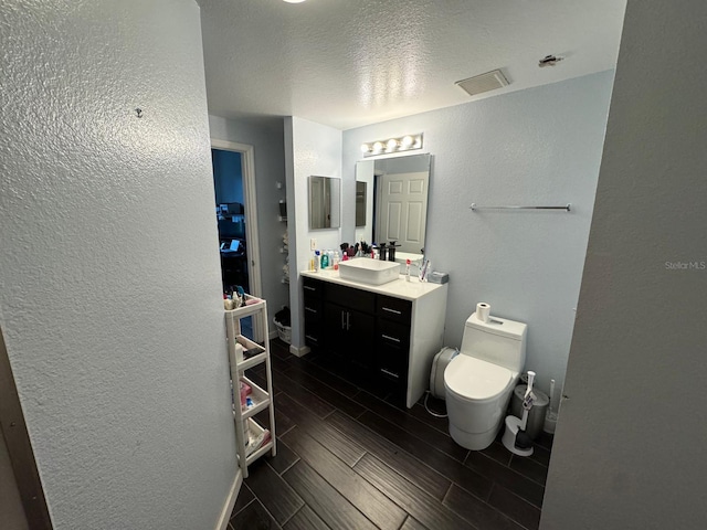 bathroom featuring vanity, toilet, and a textured ceiling