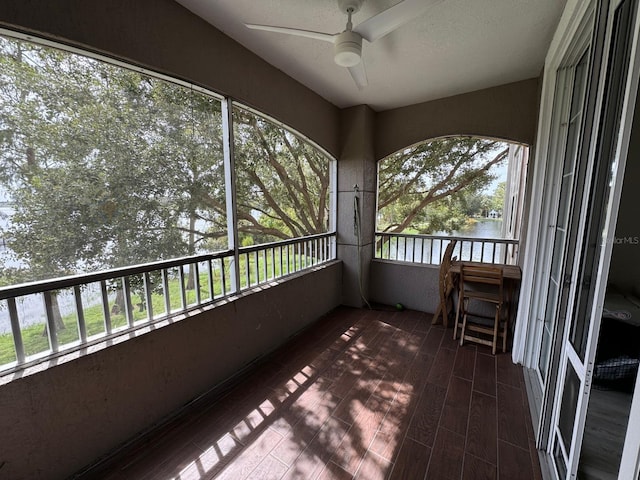 unfurnished sunroom with a water view, a wealth of natural light, and ceiling fan