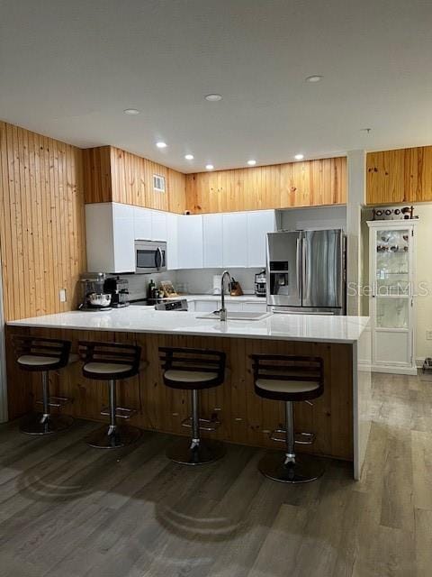 kitchen featuring dark wood-type flooring, sink, appliances with stainless steel finishes, a kitchen bar, and white cabinetry