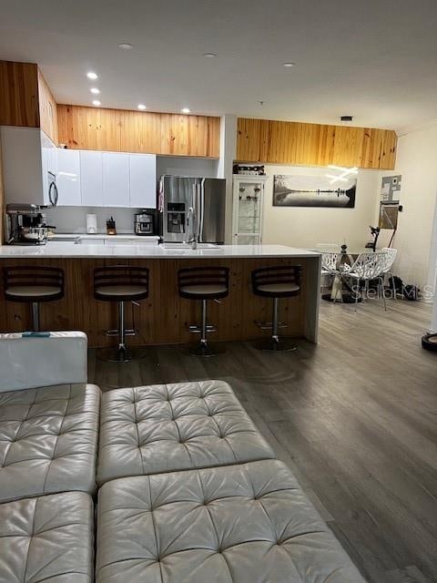 kitchen featuring kitchen peninsula, stainless steel refrigerator with ice dispenser, a kitchen bar, and dark hardwood / wood-style flooring