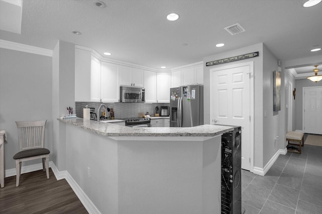 kitchen featuring appliances with stainless steel finishes, kitchen peninsula, crown molding, and white cabinets