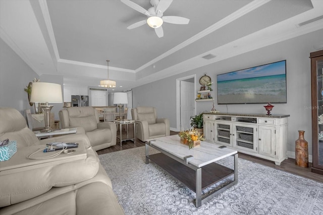 living room featuring wood-type flooring, crown molding, a tray ceiling, and ceiling fan