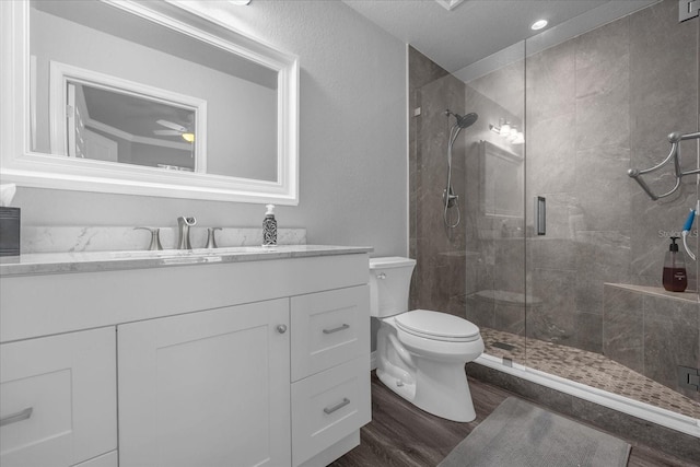 bathroom with ceiling fan, vanity, toilet, walk in shower, and hardwood / wood-style floors