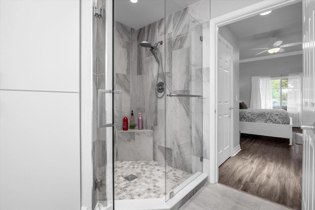 bathroom featuring ornamental molding, hardwood / wood-style flooring, ceiling fan, and a shower with door