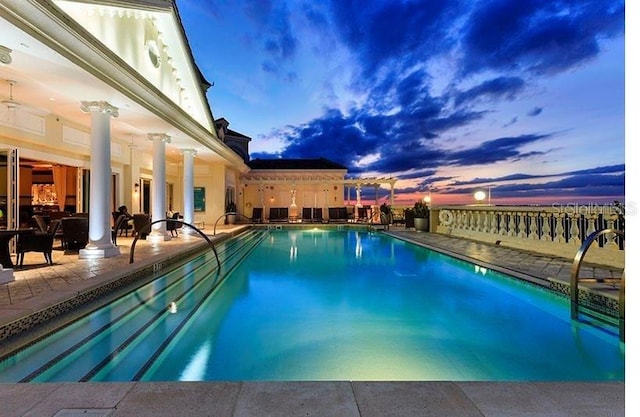 pool at dusk featuring a patio