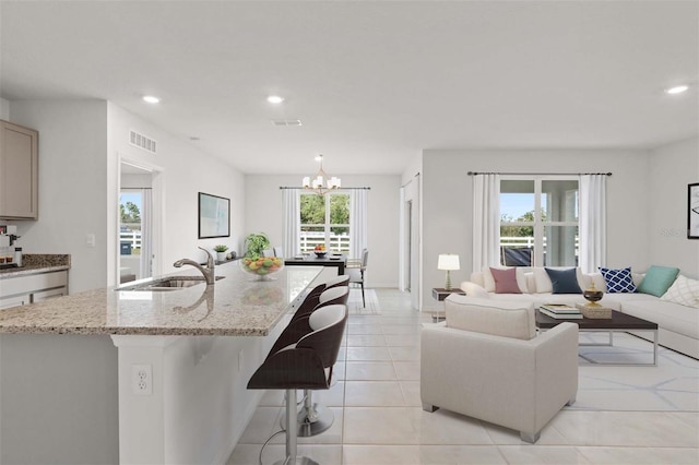 living room featuring a notable chandelier, sink, and light tile patterned floors