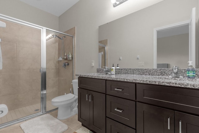 bathroom with a shower with door, vanity, toilet, and tile patterned floors