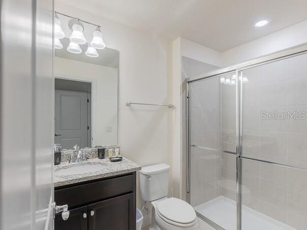 bathroom featuring an enclosed shower, vanity, and toilet