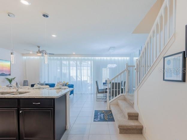 kitchen with ceiling fan, pendant lighting, sink, light stone countertops, and light tile patterned floors