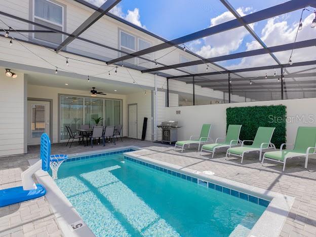 view of pool featuring glass enclosure, a patio area, and ceiling fan