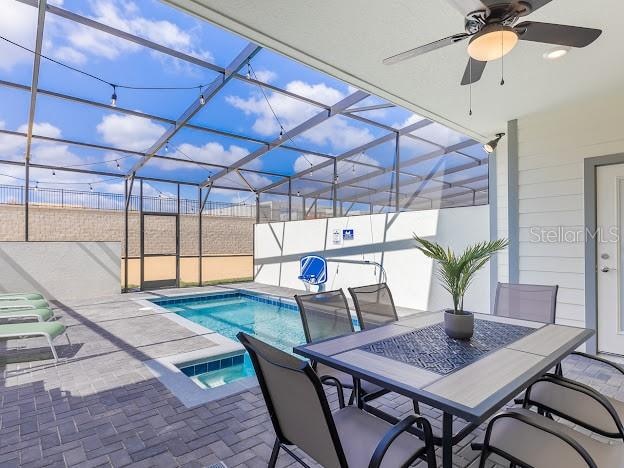 view of swimming pool with ceiling fan, glass enclosure, and a patio