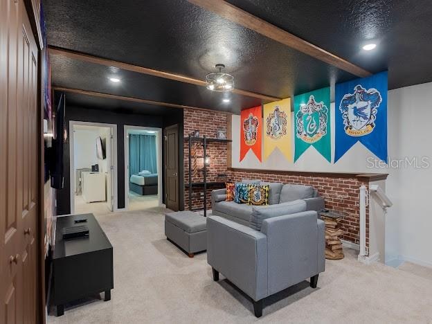 carpeted home theater room with brick wall and a textured ceiling