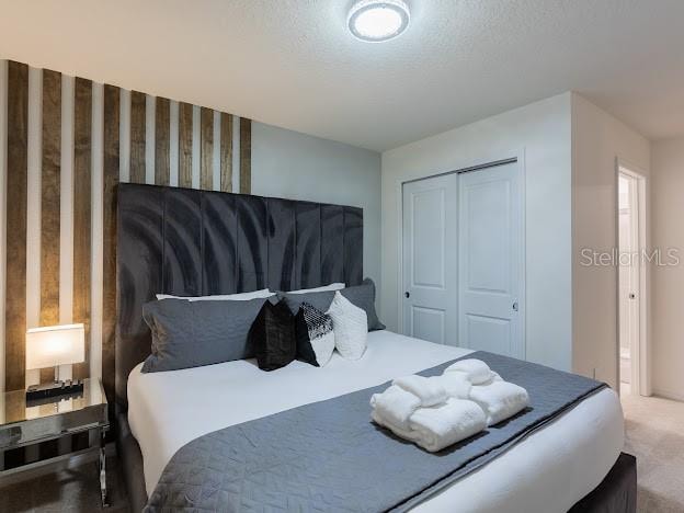 carpeted bedroom with a textured ceiling and a closet