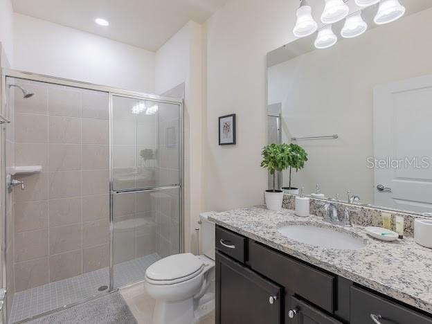 bathroom featuring vanity, toilet, and a shower with shower door