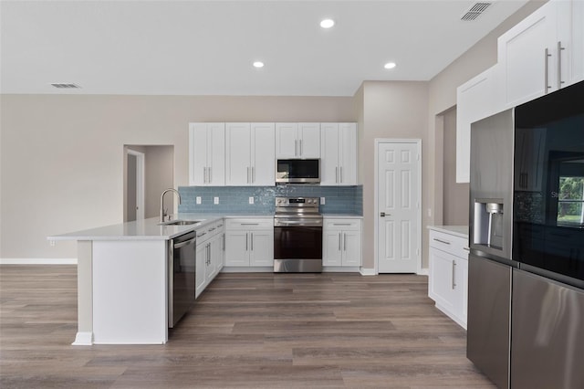 kitchen featuring dark hardwood / wood-style floors, stainless steel appliances, sink, white cabinetry, and backsplash