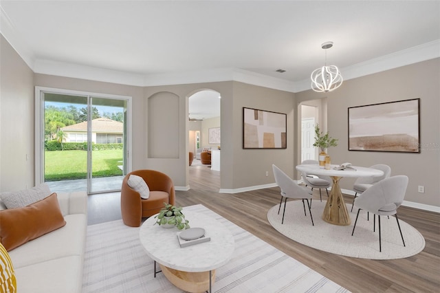 dining area featuring wood-type flooring, crown molding, and a chandelier