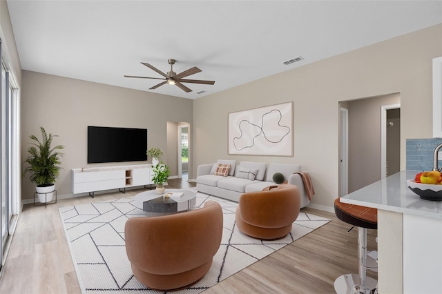 living room featuring ceiling fan, a wealth of natural light, and light hardwood / wood-style floors