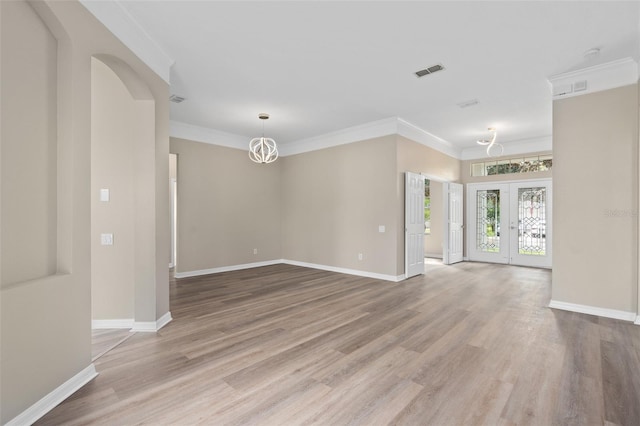 empty room featuring light wood-type flooring, crown molding, and french doors