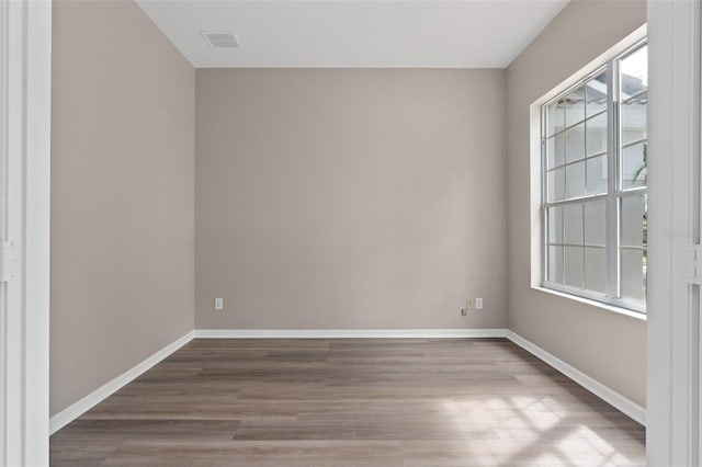 unfurnished room with hardwood / wood-style flooring and a healthy amount of sunlight