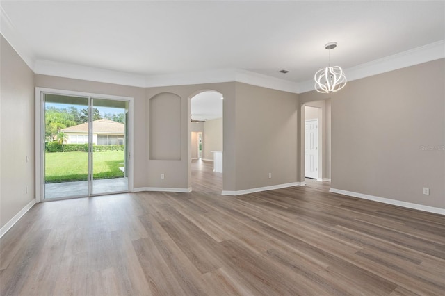 empty room with a notable chandelier, crown molding, and hardwood / wood-style flooring