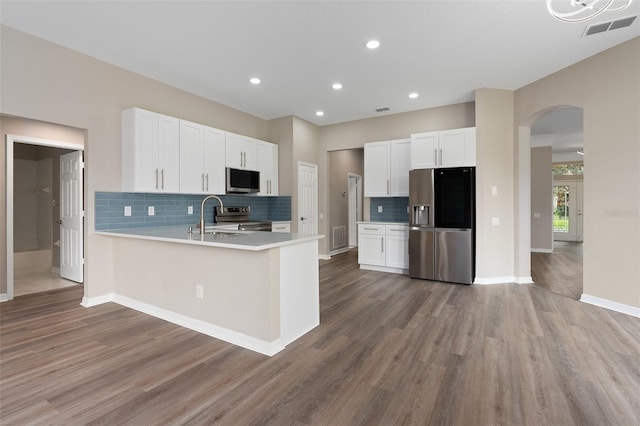 kitchen featuring hardwood / wood-style flooring, appliances with stainless steel finishes, kitchen peninsula, and white cabinetry