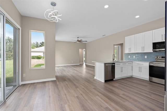 kitchen featuring light wood-type flooring, stainless steel appliances, hanging light fixtures, and kitchen peninsula