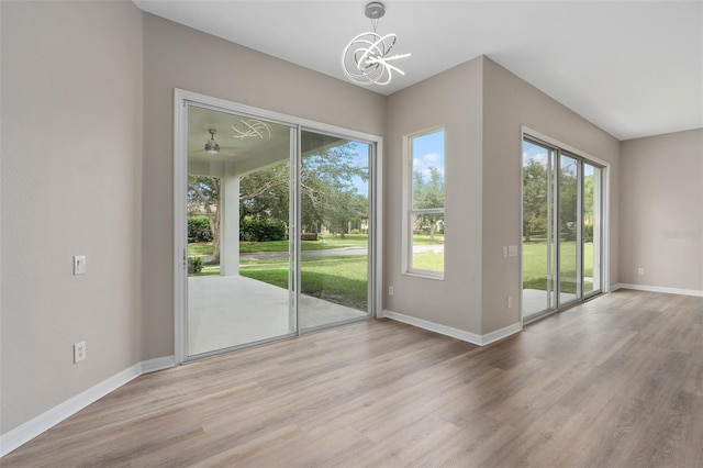 doorway to outside with ceiling fan with notable chandelier and light hardwood / wood-style flooring