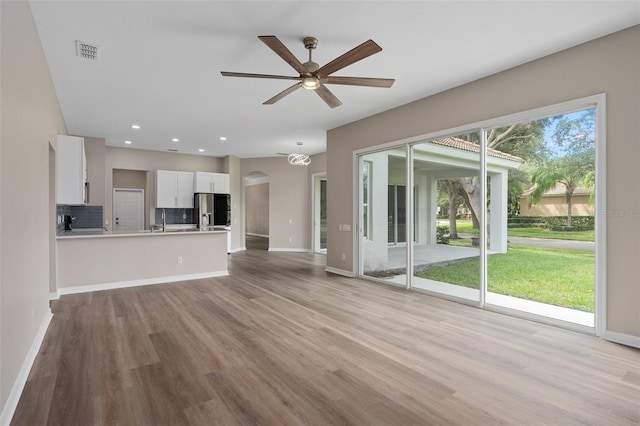 unfurnished living room with ceiling fan, sink, plenty of natural light, and light hardwood / wood-style floors