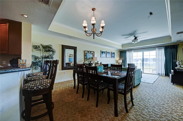 carpeted dining room featuring ornamental molding, ceiling fan with notable chandelier, and a raised ceiling