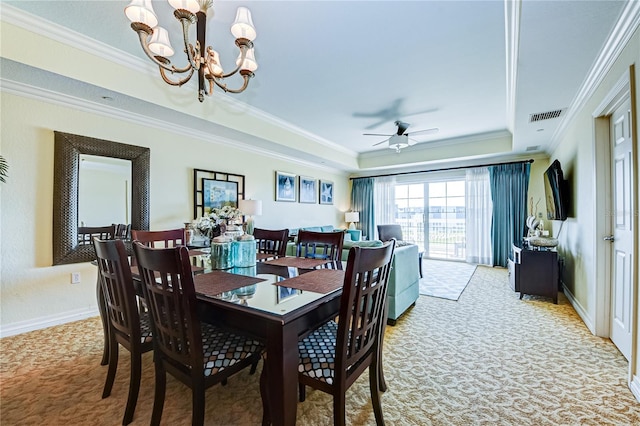 dining room featuring crown molding, light carpet, a tray ceiling, and ceiling fan with notable chandelier