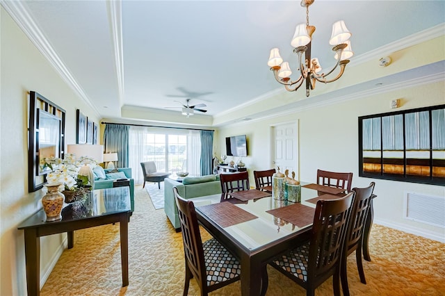 dining space with crown molding, a raised ceiling, light carpet, and ceiling fan with notable chandelier