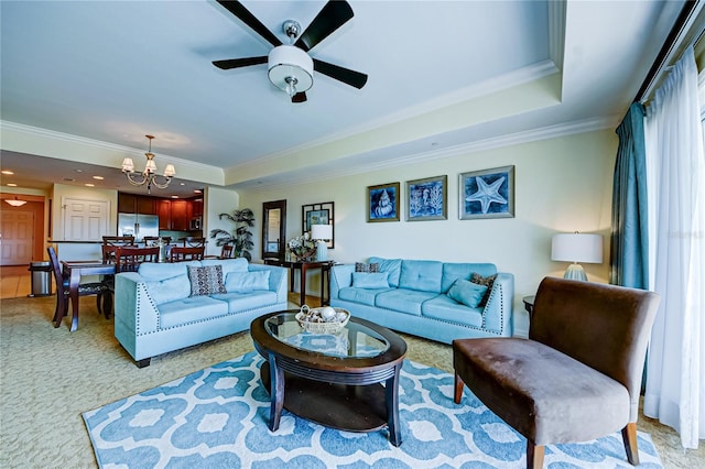 living room featuring crown molding, a tray ceiling, and ceiling fan with notable chandelier