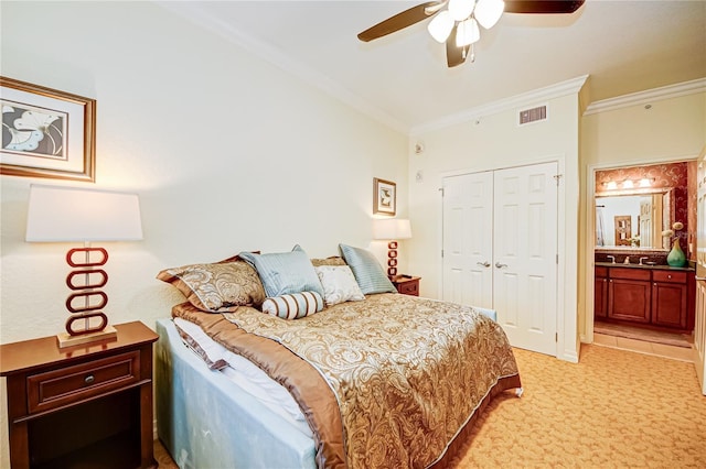 carpeted bedroom featuring crown molding, a closet, ensuite bathroom, and ceiling fan