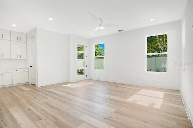 empty room featuring ceiling fan, light hardwood / wood-style floors, and a wealth of natural light