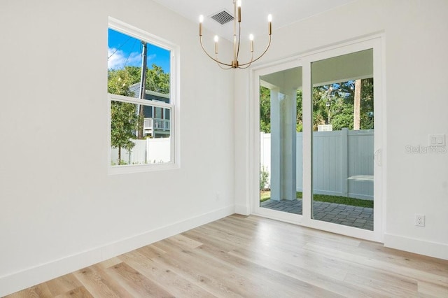 interior space with a wealth of natural light, an inviting chandelier, and light hardwood / wood-style flooring