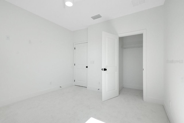 unfurnished bedroom with a closet and light colored carpet