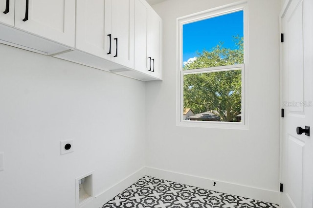 laundry area featuring tile patterned floors, hookup for an electric dryer, and cabinets