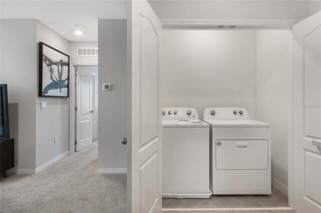 clothes washing area featuring independent washer and dryer and light colored carpet