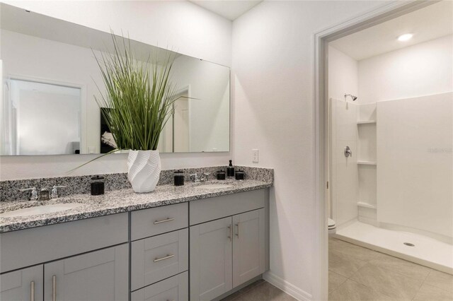 bathroom with tile patterned flooring, walk in shower, vanity, and toilet