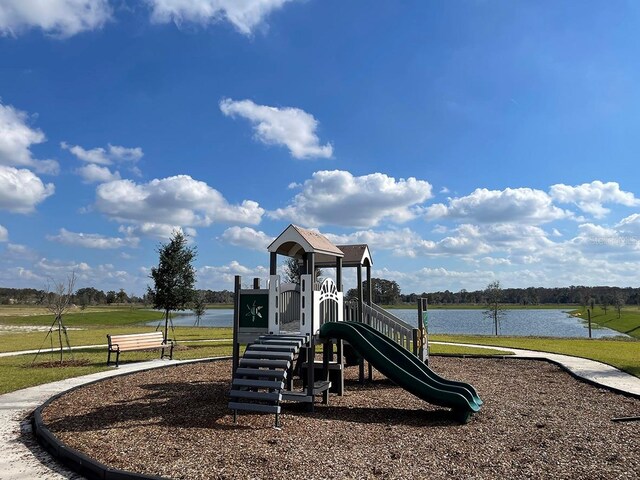 view of play area with a lawn and a water view