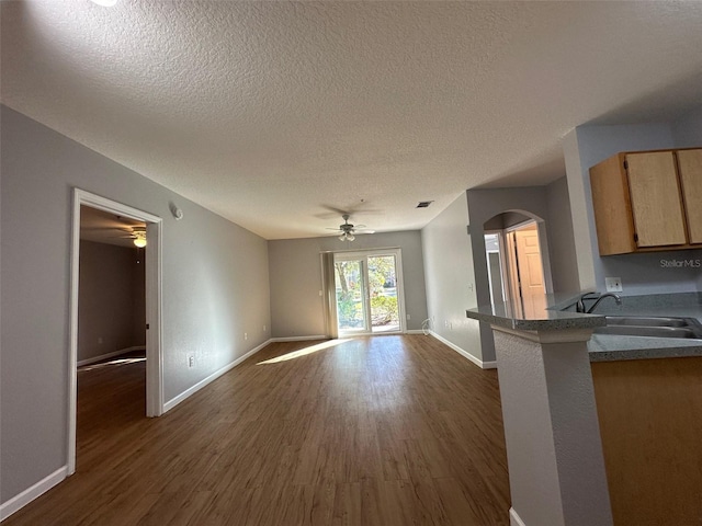 unfurnished living room with dark hardwood / wood-style flooring, a textured ceiling, and sink