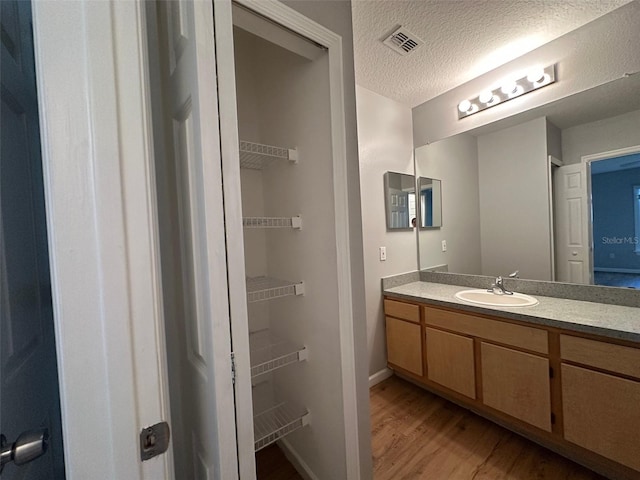 bathroom featuring hardwood / wood-style floors, vanity, and a textured ceiling