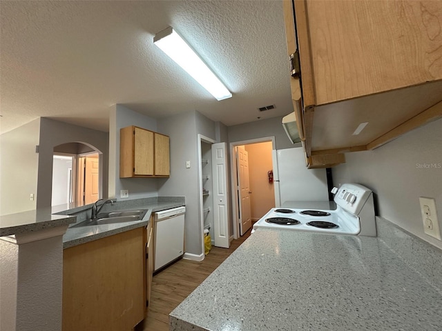 kitchen with white appliances, sink, a textured ceiling, light hardwood / wood-style floors, and kitchen peninsula