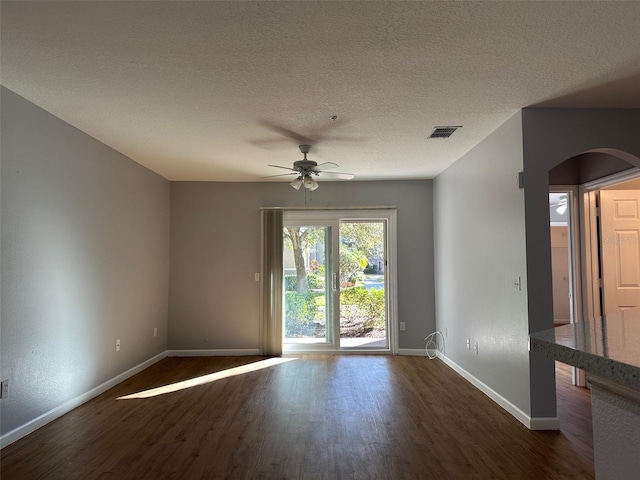 unfurnished room featuring a textured ceiling, ceiling fan, and dark wood-type flooring