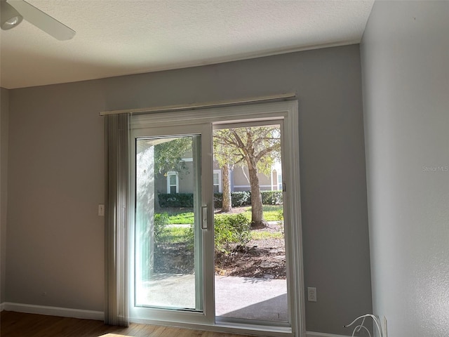 doorway with hardwood / wood-style floors, ceiling fan, and a textured ceiling