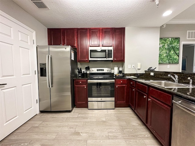 kitchen with appliances with stainless steel finishes, light hardwood / wood-style flooring, a textured ceiling, and sink