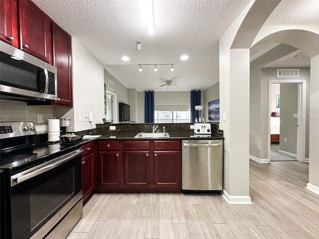 kitchen featuring appliances with stainless steel finishes, a textured ceiling, sink, and light hardwood / wood-style floors